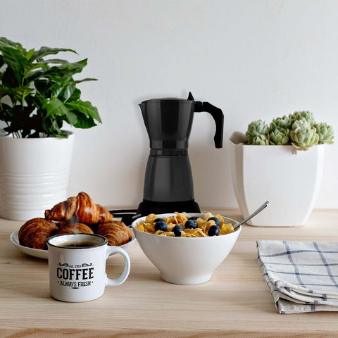 Caffettiera Elettrica DeMaison nera 6 tazze in ambiente colazione con tazza di caffè, croissant e cereali, moka elettrica elegante per una perfetta prima colazione quotidiana